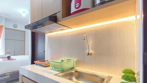 A modern kitchen with a stainless steel sink, a built-in range hood, and a countertop with a dish rack. - 2 Pax Practical Studio At Suncity Residence (Sidoarjo)