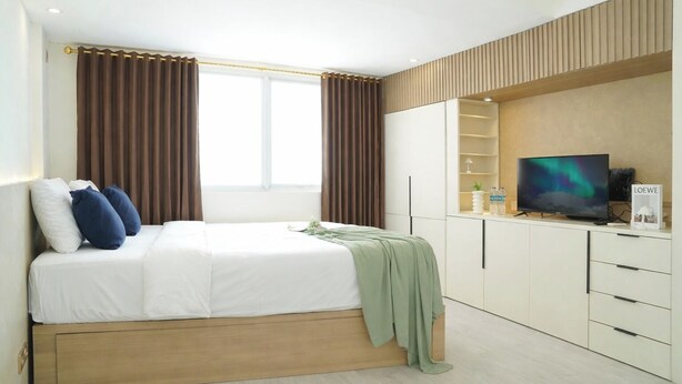 A modern hotel room with a bed, a television, and a wardrobe. - Neat Studio At Amethyst Apartment Near Jiexpo (Jakarta)