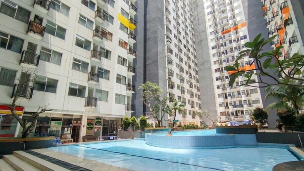 Edificio residencial con varios balcones, piscina y zonas verdes.