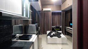 Een compacte hotelkamer met kitchenette, een bed, bureau en televisie.