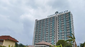 Een hoog hotelgebouw met de naam 'TAMAN MELATI' op de gevel.
