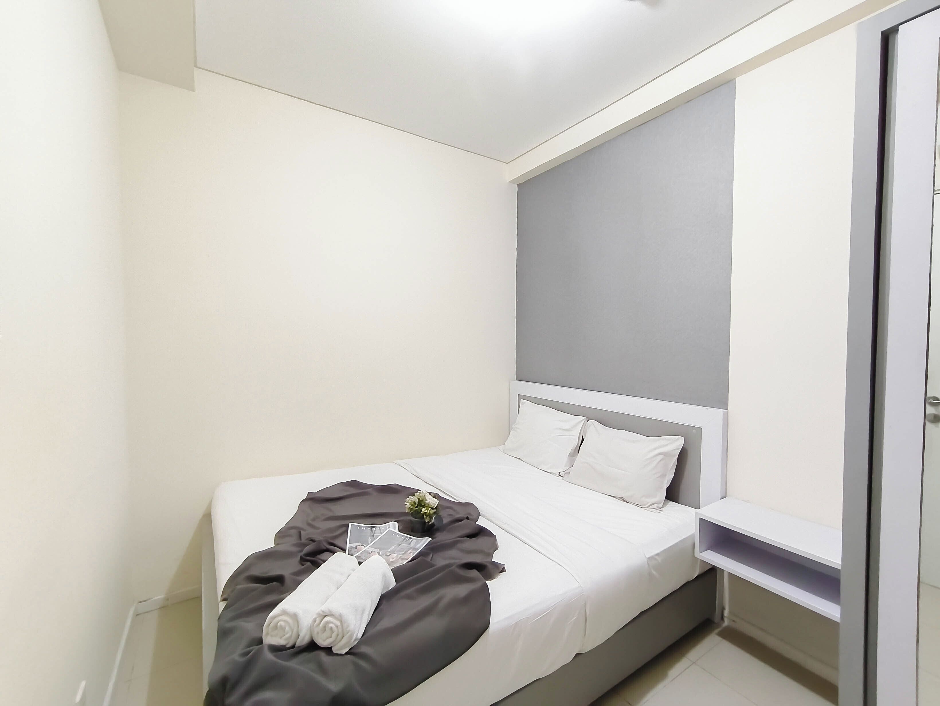 Een hotelkamer met een bed, nachtkastje, een plantje en een handdoek.