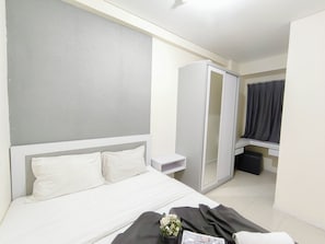 A hotel room with a bed, a wardrobe, a bedside table, and a window with curtains. - Bright And Simple 2Br Apartment At Parahyangan Residence (Bandung)