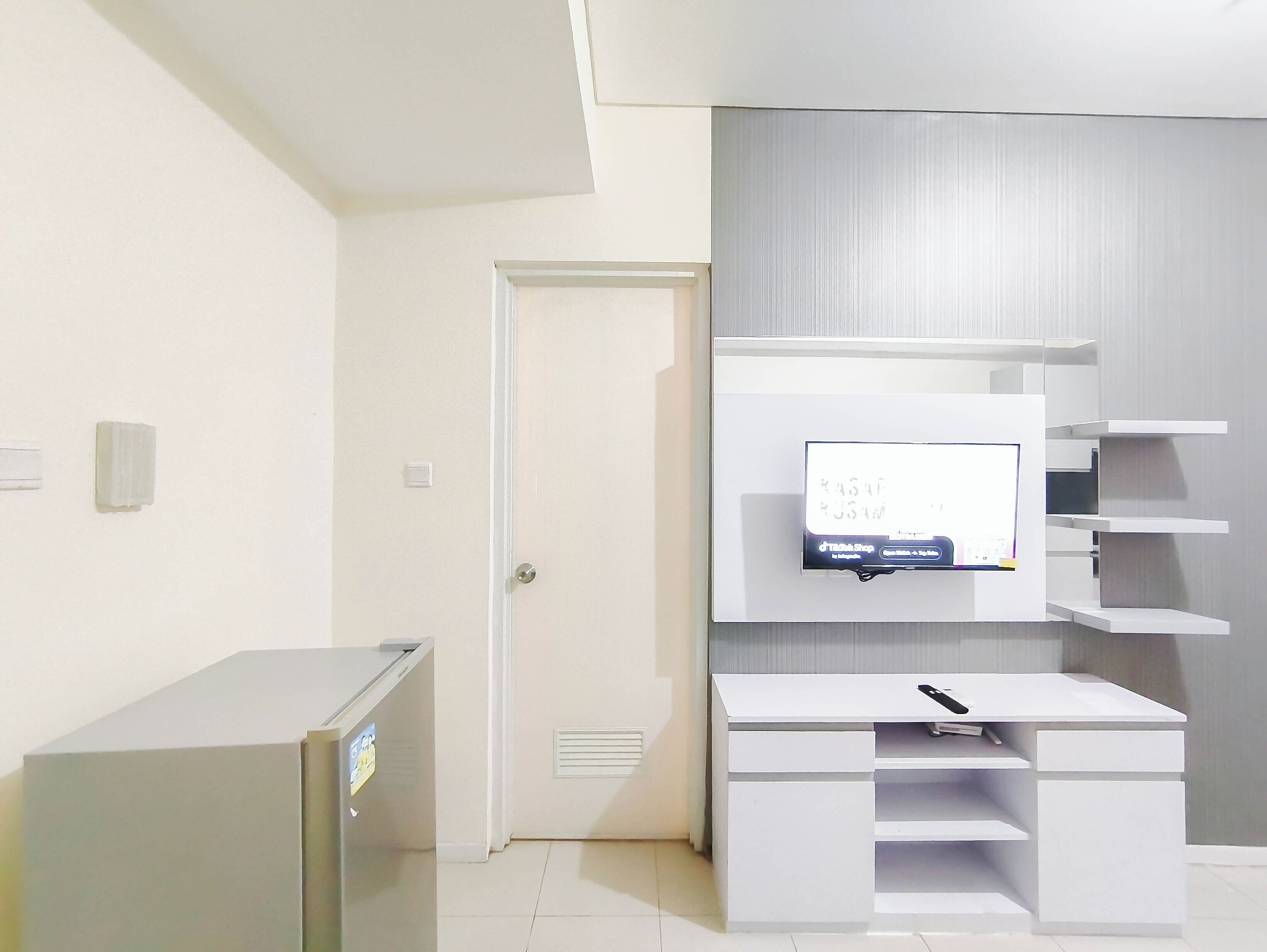 A modern room with a white desk, a flat-screen TV mounted on the wall, and a door.