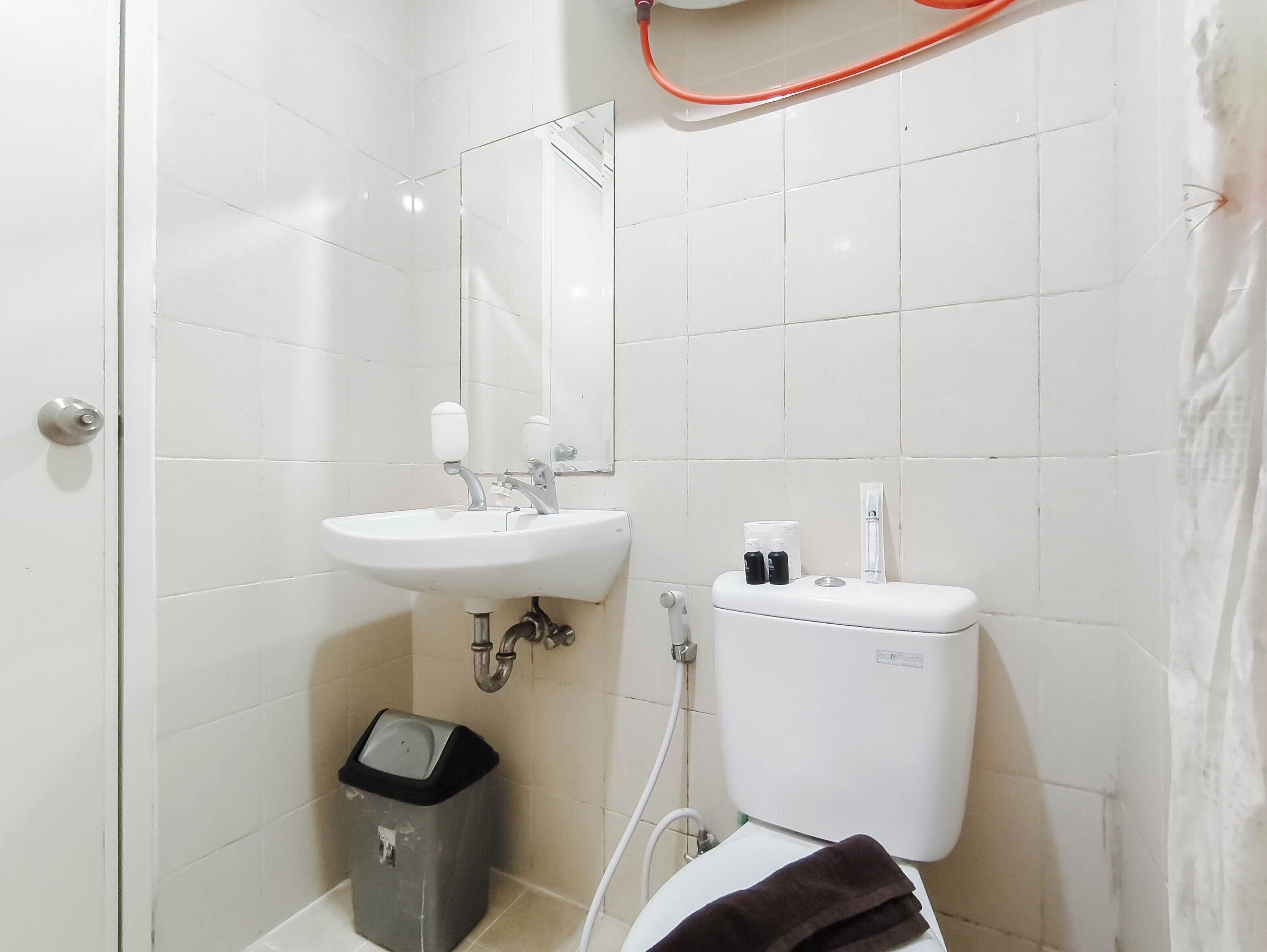 Ein Badezimmer mit weißem Waschbecken, Spiegel, Toilette und Mülleimer.