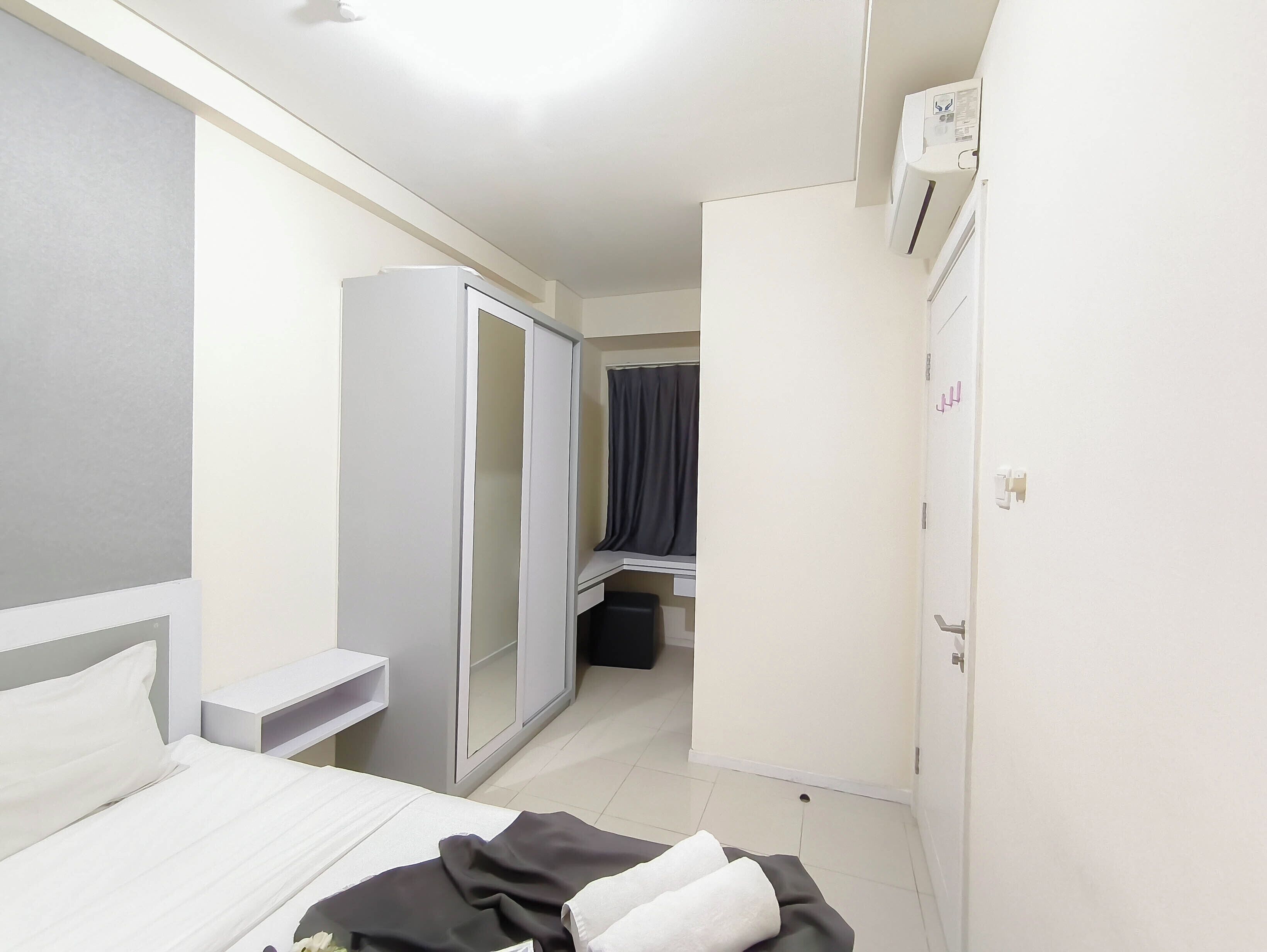 A hotel room with a bed, a wardrobe, a mirror, a curtain, and an air conditioning unit.