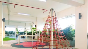 A gym with exercise equipment, including a climbing structure, and a green outdoor area with plants. - Good And Comfy Studio Apartment At Grand Kamala Lagoon (Bekasi)