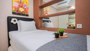 Ein Hotelzimmer mit Bett, Spiegel, einem Wandbild einer Blume und zwei Blumentöpfen.