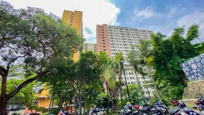 A high-rise building with balconies, surrounded by lush greenery and parked scooters. - Practical 2Br For 3 Pax At Kebagusan City Apartment (Jakarta)