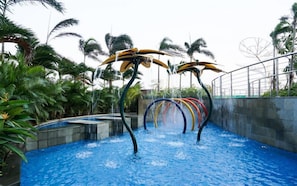 A water park with a pool, water slides, and palm trees. - Neat Urban Style Studio Room At Apartment West Vista (Jakarta)