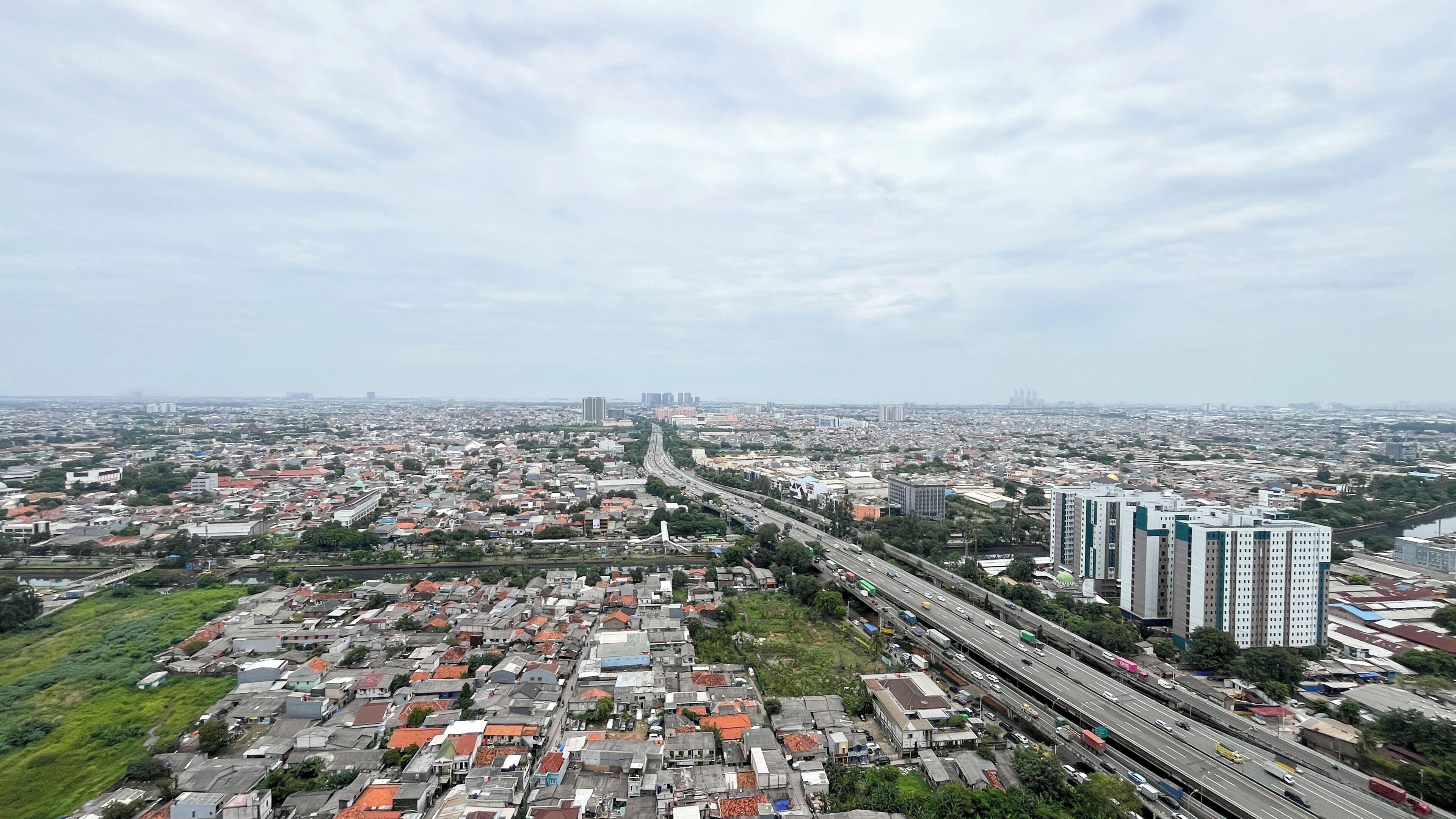 Un paisaje urbano con una autopista, zonas residenciales y edificios altos.