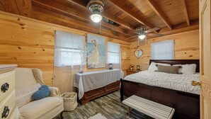 A wooden cabin bedroom with a bed, dresser, bench, and a ceiling fan. - Cozy 1-bedroom cabin in perfect Hudson with cool AC (Hudson)