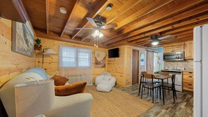 A cozy cabin interior with a dining area, kitchen, and a ceiling fan. - Cozy 1-bedroom cabin in perfect Hudson with cool AC (Hudson)