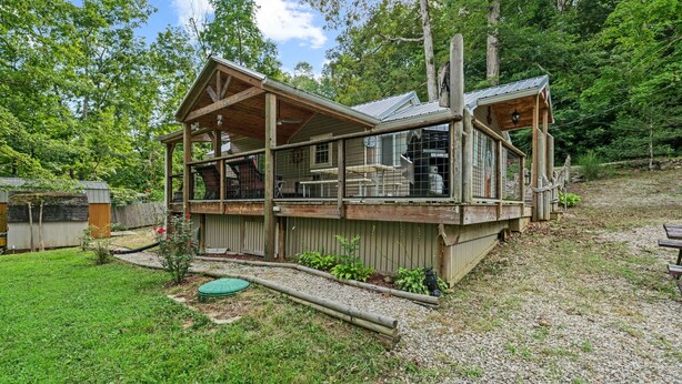 A wooden cabin with a covered porch, a fenced-in area, and a gravel driveway. - Cozy 1-bedroom cabin in perfect Hudson with cool AC (Hudson)
