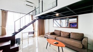Uma sala de estar moderna com escada, um sofá, uma mesa de centro e uma televisão fixada na parede.