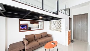 Uma sala de estar moderna com um sofá, uma mesa de centro, uma televisão e um painel decorativo na parede.