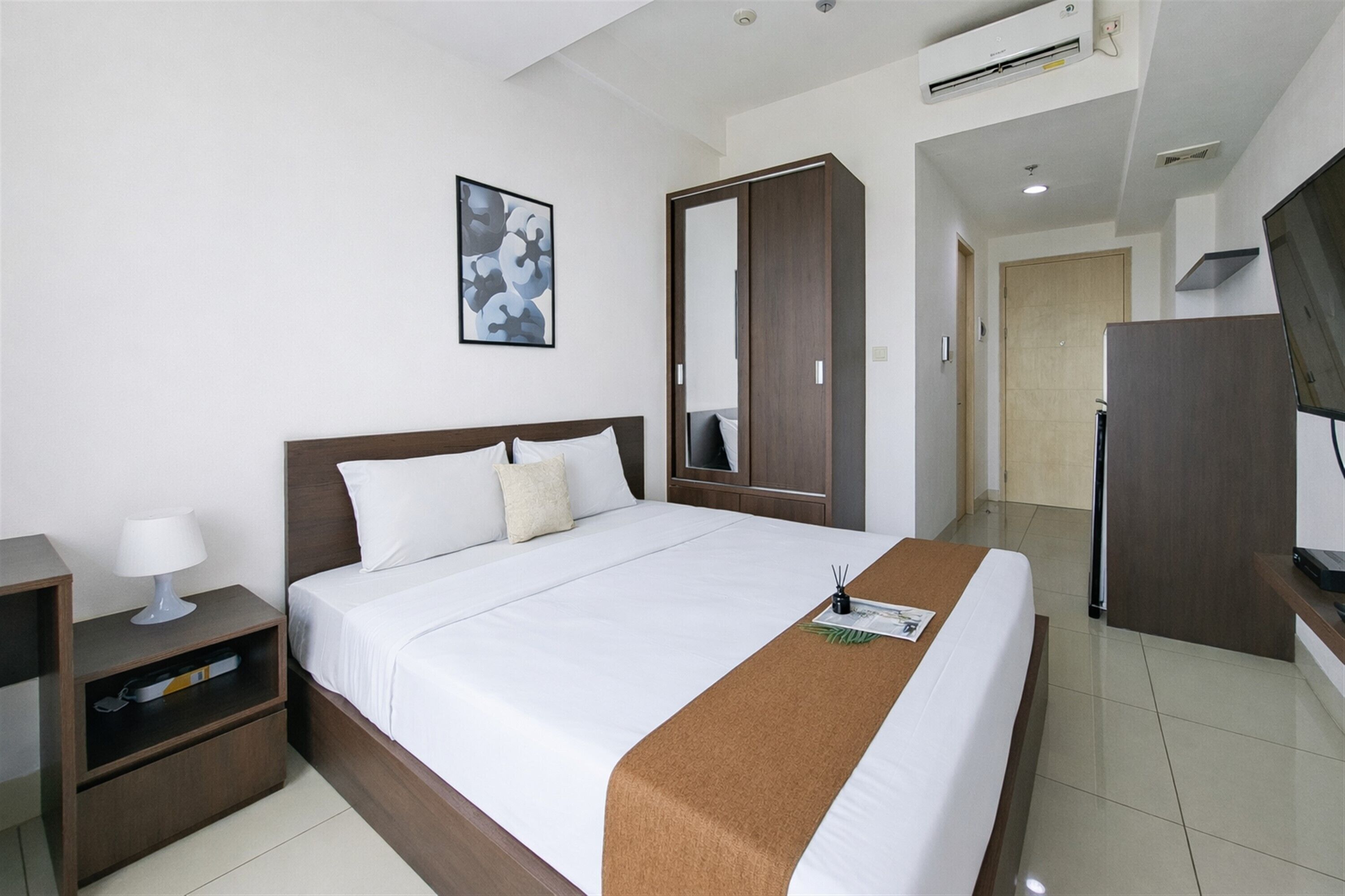 Habitación de hotel con cama, mesita de noche, armario y televisor.
