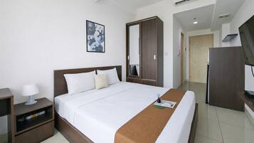 Habitación de hotel con cama, mesita de noche, armario y televisor.