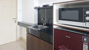 Eine kleine Küche mit Mikrowelle, Spüle und kompaktem Kühlschrank.