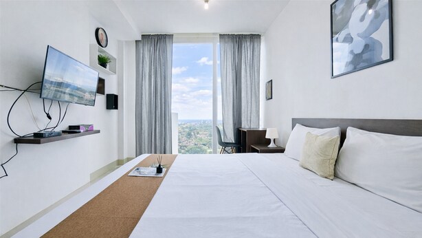 Ein Hotelzimmer mit Bett, Fernseher, Schreibtisch und Blick auf die Stadt.