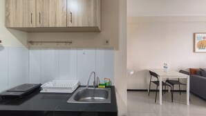 A modern kitchen with a black countertop, stainless steel sink, and wooden cabinets. - Neat And Restful 2Br At Gateway Pasteur Apartment (Cimahi)