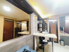 Quarto de hotel com banheiro, pia, espelho, uma cadeira preta e uma lixeira.