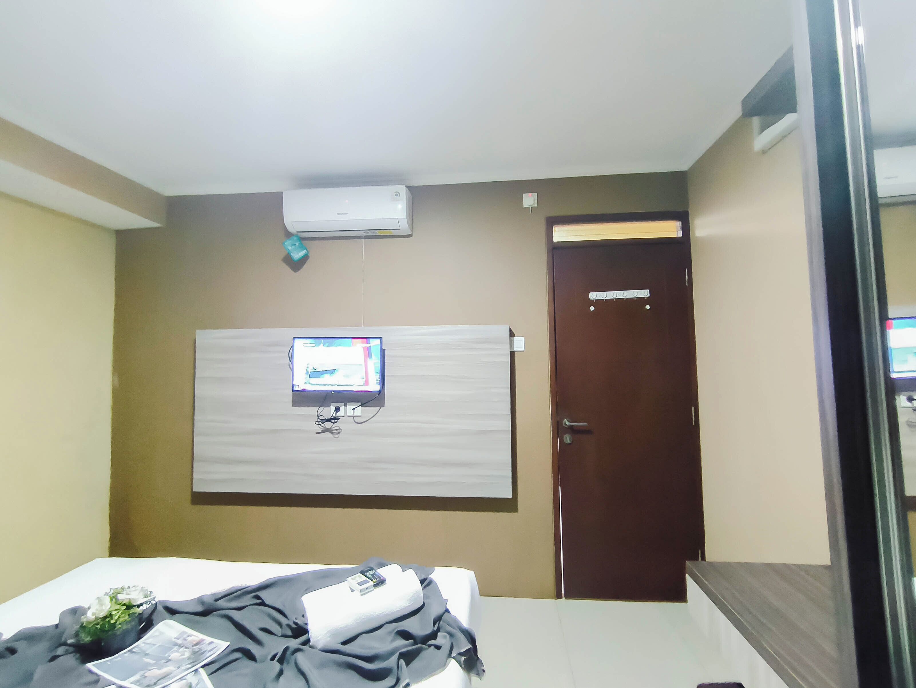 Une chambre d’hôtel équipée d’un lit, d’un téléviseur fixé au mur, d’une porte et d’un appareil de climatisation.