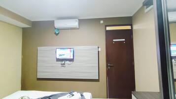 Une chambre d’hôtel équipée d’un lit, d’un téléviseur fixé au mur, d’une porte et d’un appareil de climatisation.