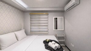 Une chambre d’hôtel avec un lit, une fenêtre avec des stores, un miroir et un appareil de climatisation.