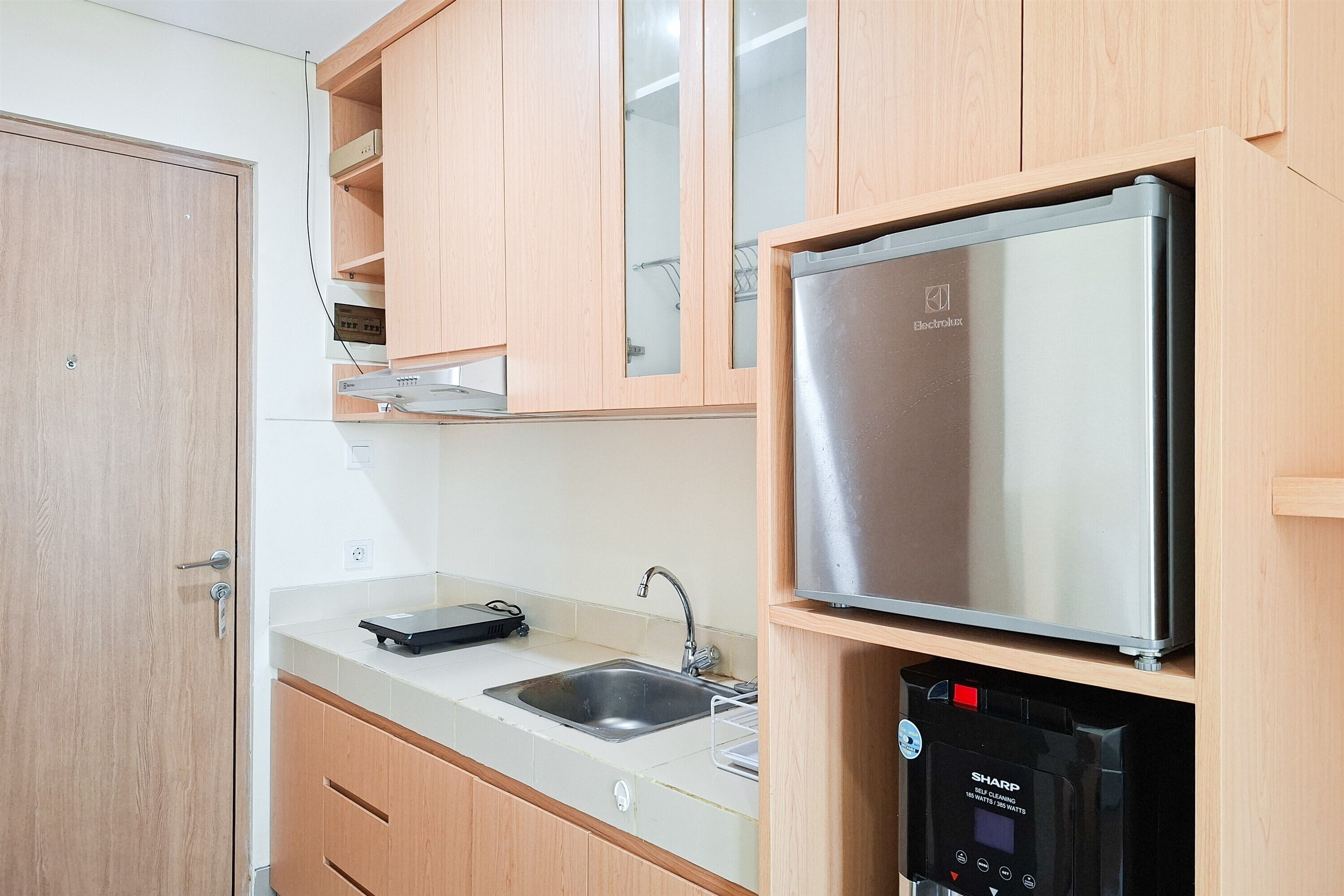 Una cocina con armarios de madera, un refrigerador de acero inoxidable, un fregadero y un dispensador de agua.