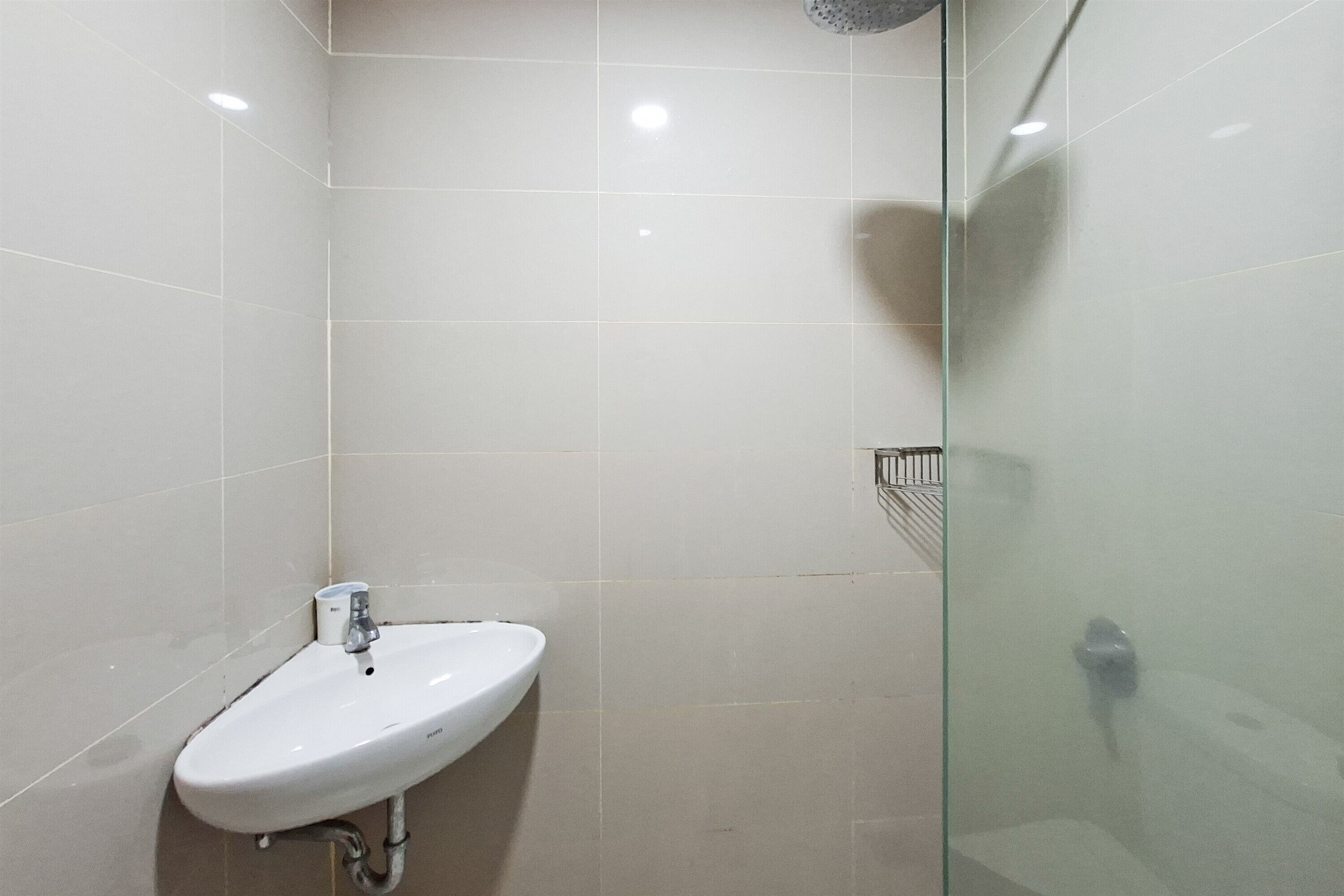 A bathroom with a white sink, a glass shower enclosure, and tiled walls.