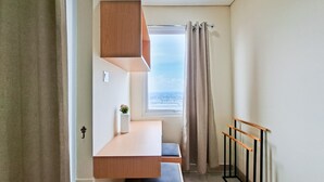 Habitació amb escriptori integrat, finestra amb cortines i radiador.