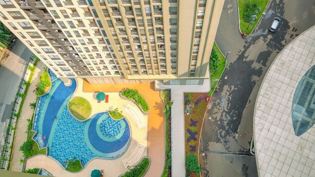 A high-rise building with a rooftop pool and surrounding greenery. - Comfortable 1Br With Extra Room At Transpark Cibubur Apartment (Bekasi)