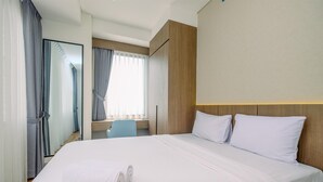 A hotel room with a large bed, a desk, and a mirror. - Comfortable 1Br With Extra Room At Transpark Cibubur Apartment (Bekasi)