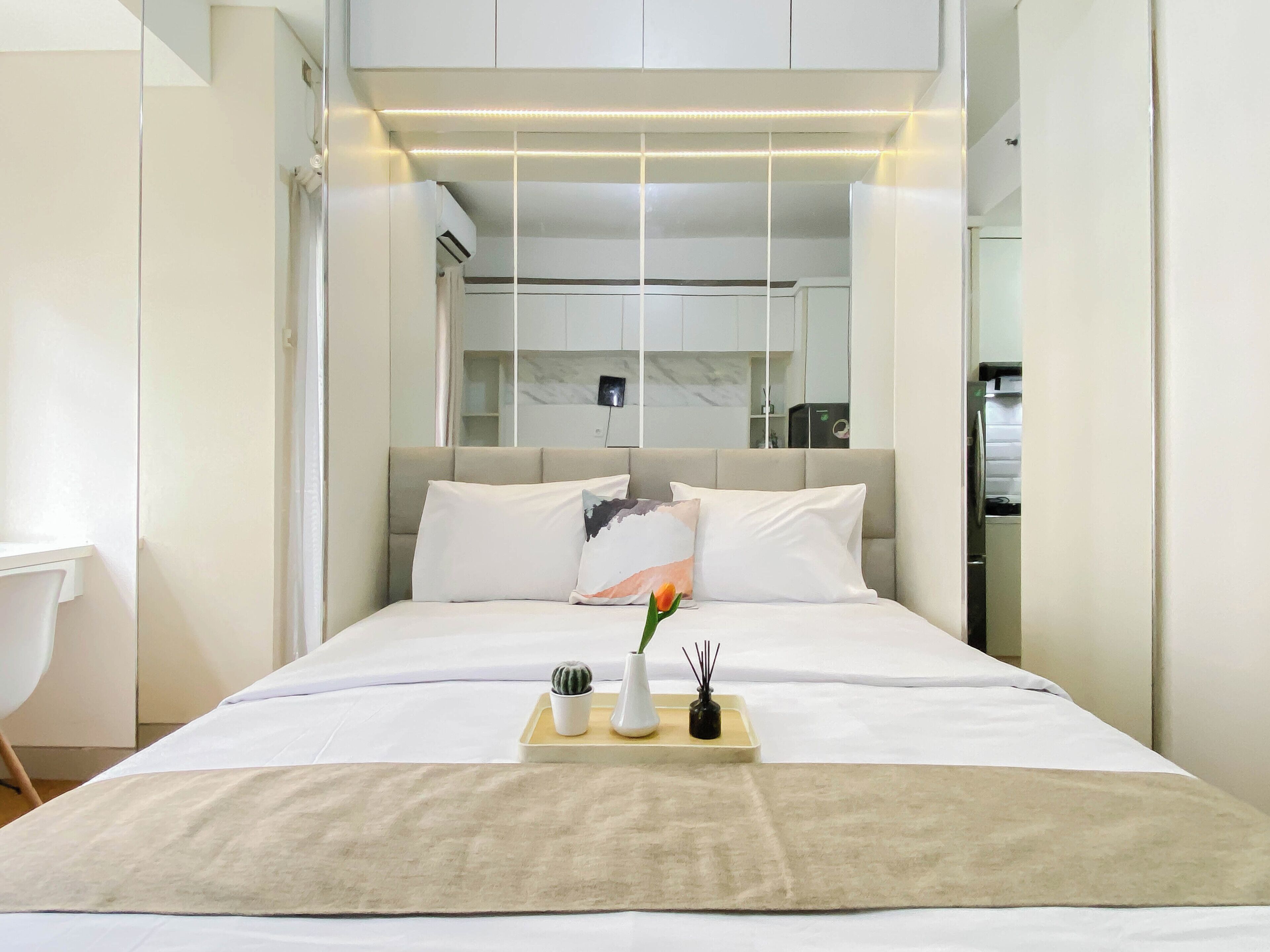 A modern hotel room with a bed, bedside table, and a small desk area.
