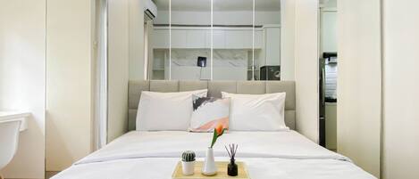 A modern hotel room with a bed, bedside table, and a small desk area.