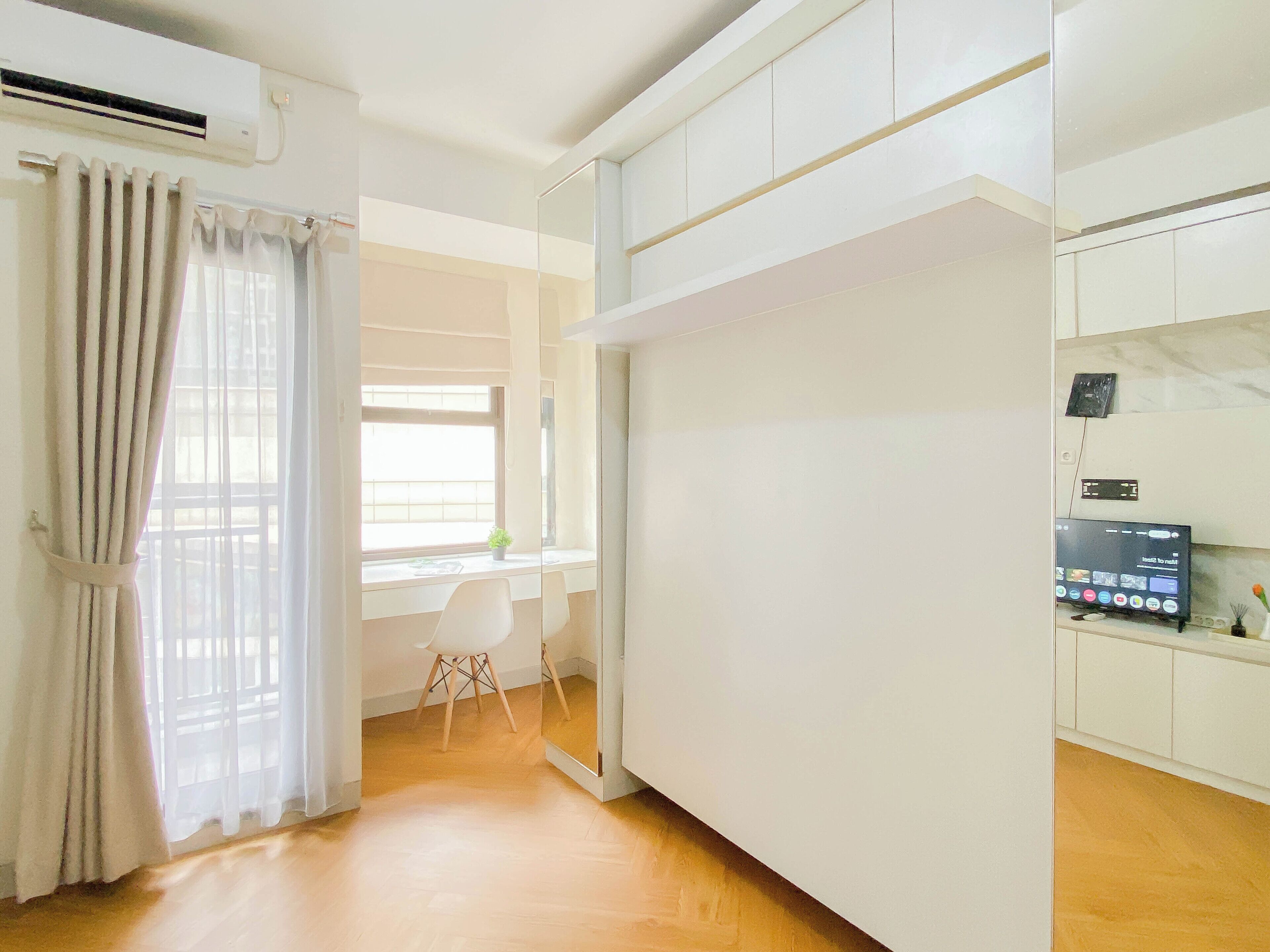 A modern kitchen with white cabinets, a built-in microwave, and a small window with a plant on the counter.