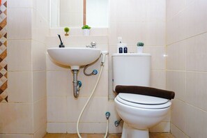 A bathroom with a sink, toilet, and a towel on the toilet. - Smart Layout Studio At Dave Apartment Near Universitas Indonesia (Depok)