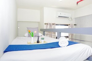 Ein Hotelzimmer mit einem Bett, einem blauen Handtuch, einem weißen Kopfkissen, einer Vase mit Blumen und einer kleinen Pflanze.