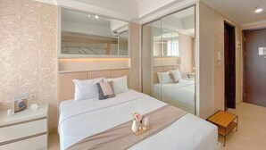 Hotellihuone, jossa on suuri sänky, yöpöytä, sängyn vieressä oleva pöytä, peili ja vaatekaappi.