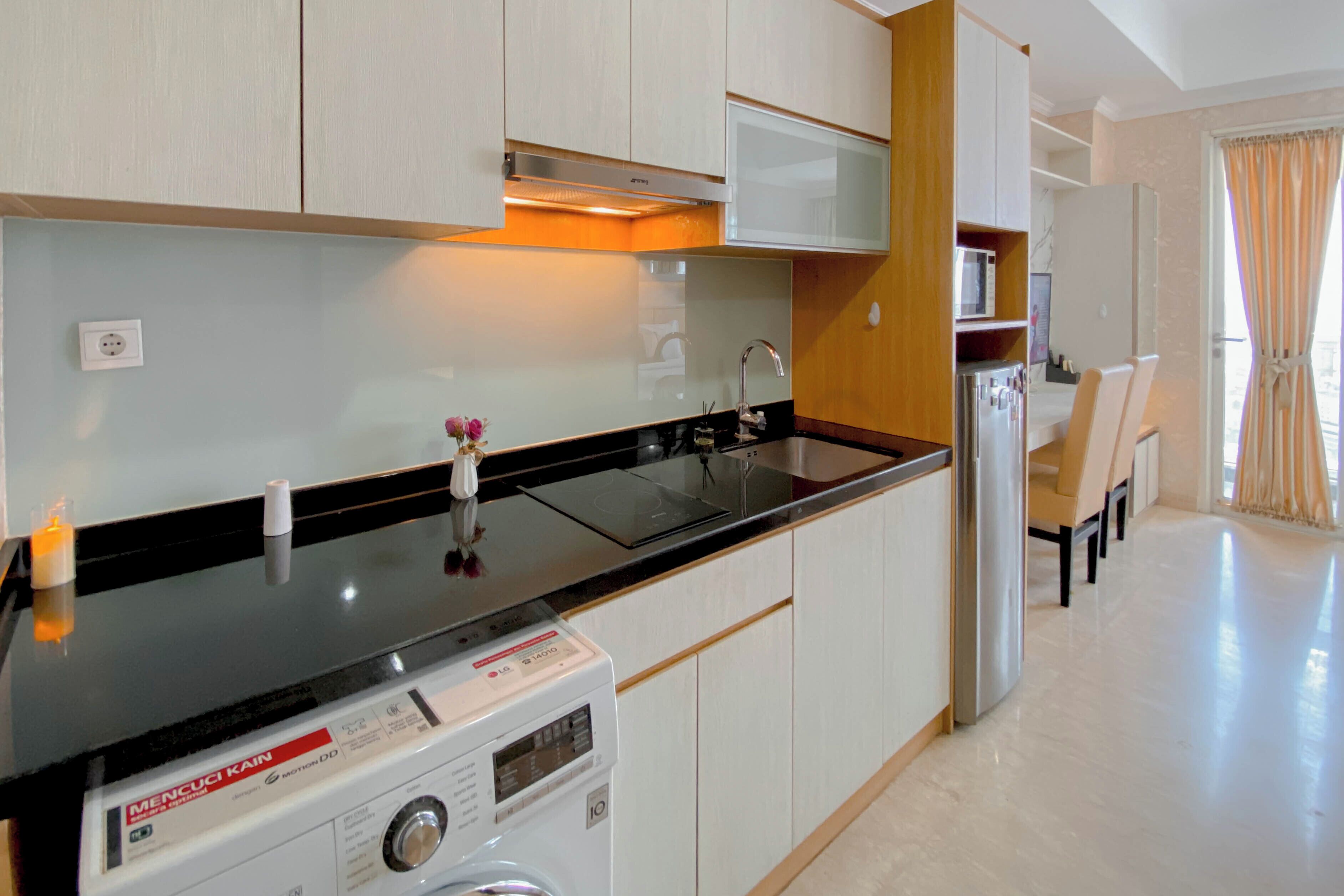 A modern kitchen with a built-in washing machine, a microwave, and a sink.