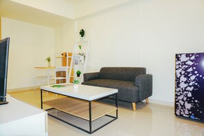 Ein modernes Wohnzimmer mit einer Couch, einem Couchtisch, einem Fernseher, einem Bücherregal und einer Wanddekoration.