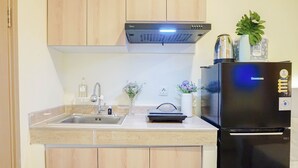 Una cocina con un lavamanos de acero inoxidable, armarios de madera, un refrigerador negro y una campana extractora empotrada.