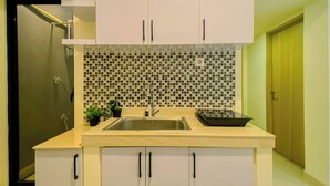 Uma cozinha com painel de azulejos, pia, armários e bancada.