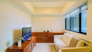 Uma sala de estar moderna com televisão, móveis de madeira, sofá e janela com persianas.