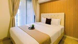 Quarto de hotel com uma cama grande, cabeceira e janela com cortinas.