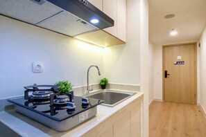 Eine moderne Küche mit einem Gaskochfeld, einer Edelstahl-Spüle und einer Holztür.