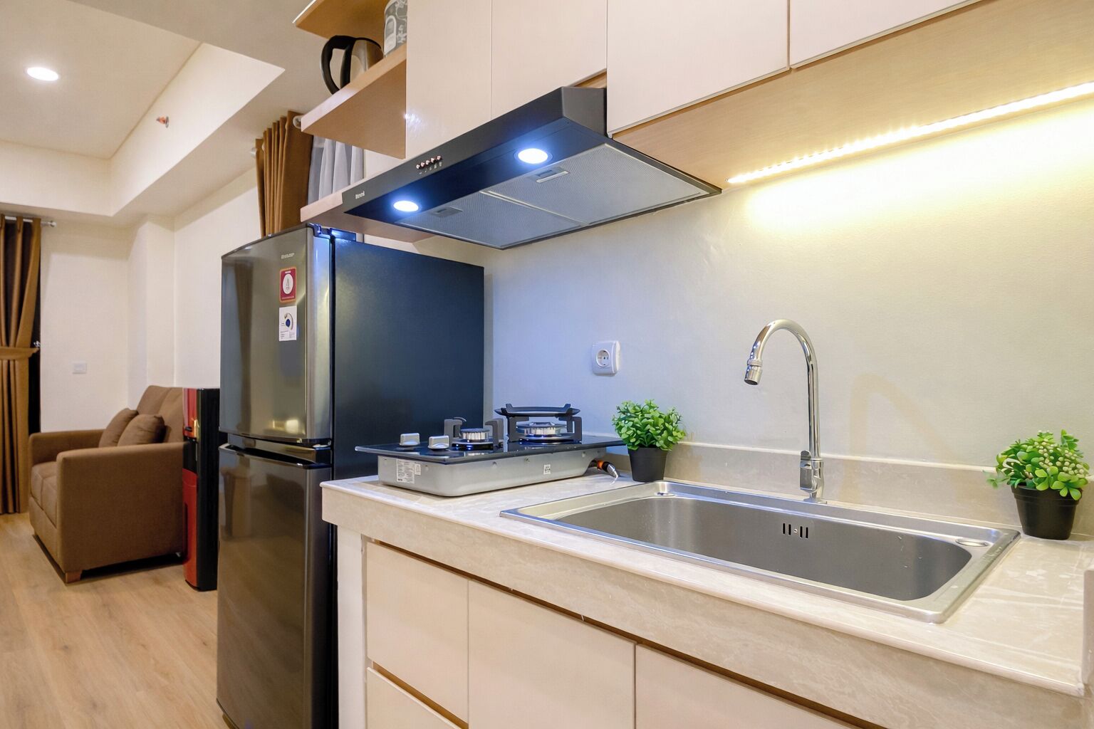 A compact kitchen with a built-in stove, a stainless steel sink, and a refrigerator.