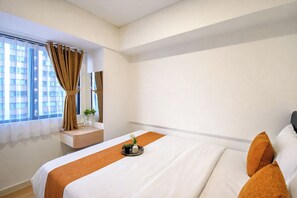 Ein Hotelzimmer mit einem großen Bett, einem Fenster mit Vorhängen, einem kleinen Tisch mit einer Vase und Blick auf Gebäude.