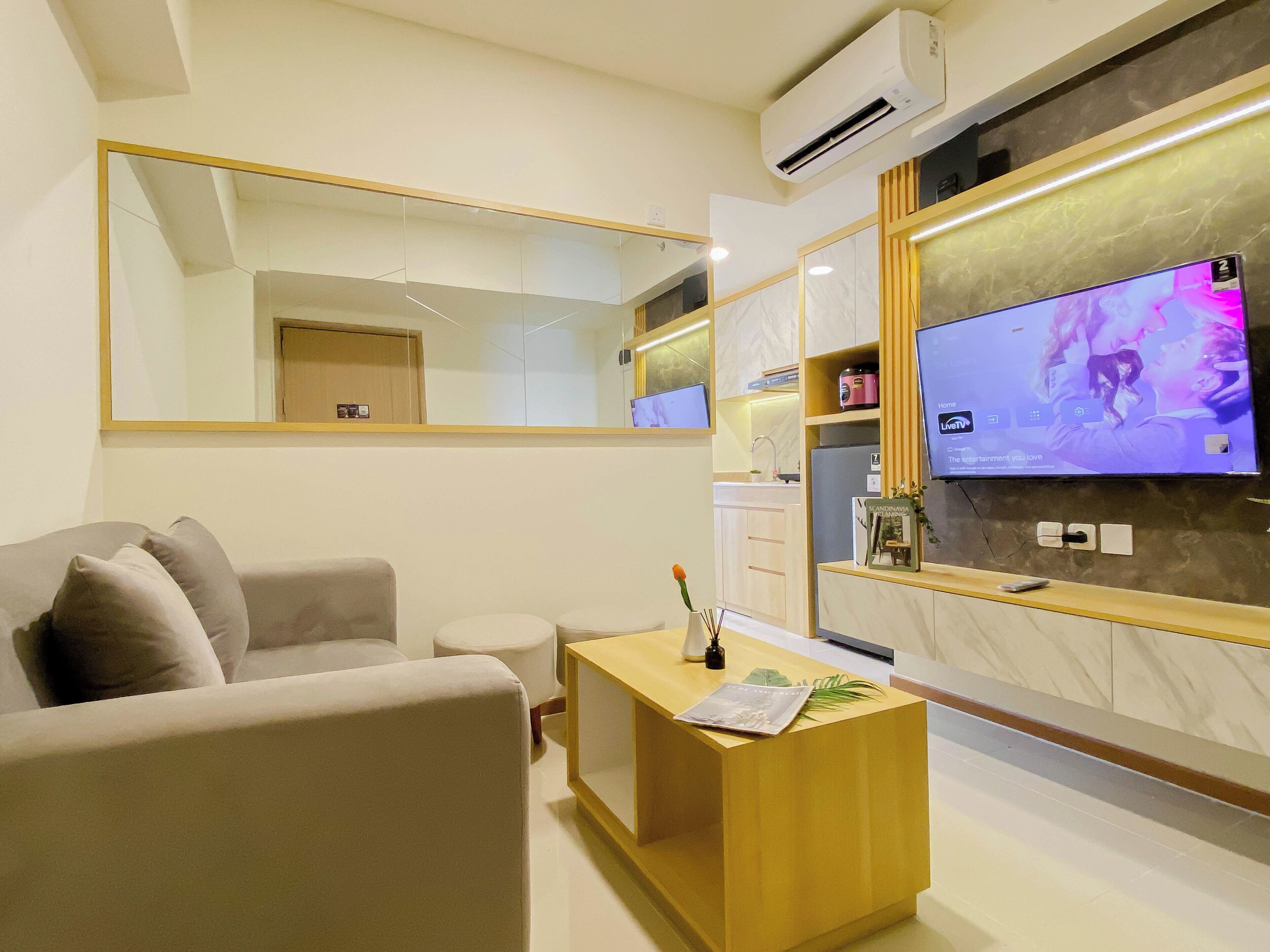 Una sala de estar moderna con un sofá, una mesa de centro, un televisor y un espejo grande.